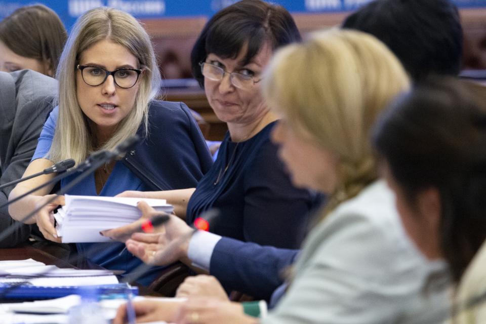 In this photo taken on July 23, 2019, Russian opposition candidate and lawyer at the Foundation for Fighting Corruption Lyubov Sobol, left, gives election documents to Ella Pamfilova, head of Russian Central Election Commission, right back to a camera, during a meeting with Opposition candidates at the Russian Central Election commission in Moscow, Russia. Pamfilova has defended the commission's decision to bar nearly two dozen candidates from running in a local Moscow election, which sparked a full-blown political crisis, but conceded that current election legislation is outdated and needs to be amended. (AP Photo/Alexander Zemlianichenko)