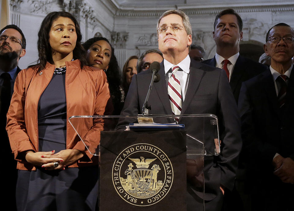 FILE - In this Dec. 12, 2017 file photo, city attorney Dennis Herrera, center, speaks at a news conference next to acting mayor London Breed, left, at City Hall in San Francisco. San Francisco officials are offering to buy Pacific Gas & Electric's power lines and other infrastructure in the city for $2.5 billion. Mayor London Breed and City Attorney Dennis Herrera presented the offer in a letter sent to the utility Friday, Sept. 6, 2019. (AP Photo/Jeff Chiu, file)