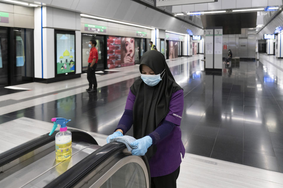 A worker disinfects the escalator at a Mass Rapid Transit train station in Kuala Lumpur, Malaysia, on Monday, May 4, 2020. Many business sectors reopened Monday in some parts of Malaysia since a partial virus lockdown began March 18. (AP Photo/Vincent Thian)