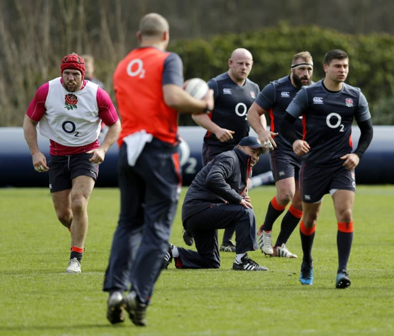 England's Coach Eddie Jones (C) takes to his knee as he watches a drill during a team training session west of London