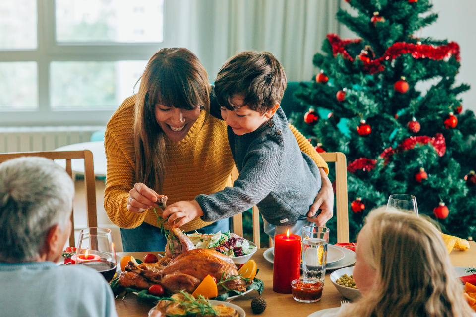 Cute little boy and his beautiful mother having fun during Christmas dinner or lunch.