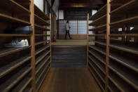 A tourist walks past shoe racks provided for visitors at Tenryuji Temple in the Arashiyama district of Kyoto, Japan, March 18, 2020. "Arashiyama is empty," is a new catchphrase that appeared on posters in the area. "It's time to visit Kyoto," they say, because there are no long lines and waiting to do river rafting, get into popular temples or cross the bridge. (AP Photo/Jae C. Hong)