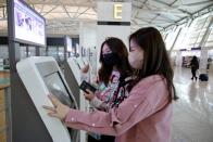 Kim Ji-eun and Lee Hyun-joo, BTS fans, check their tickets at the Incheon International Airport