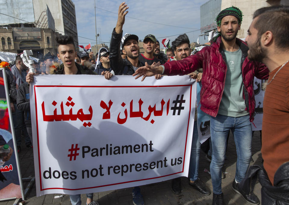 Anti government Iraqi protesters chant anti Iran and anti U.S. slogans while they carry a poster that reads in Arabic "this parliament does not represent us," during the ongoing protests in Tahrir square, Baghdad, Iraq, Friday, Jan. 10, 2020. (AP Photo/Nasser Nasser)