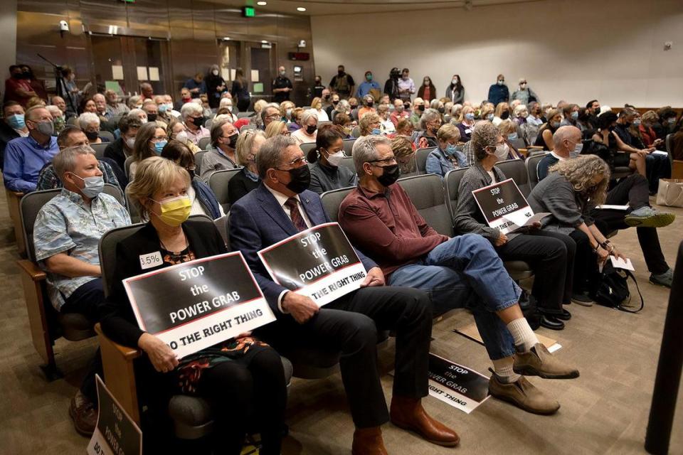 People hold signs reading “Stop the power grab: Do the right thing” at the San Luis Obispo County Board of Supervisors on Tuesday, Nov. 30, 2021, as it considers the two finalist redistricting maps.