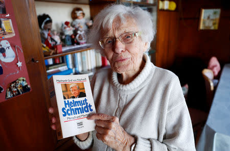 Lisel Heise, a 100-year-old former teacher, holds a book about former German Chancellor Helmut Schmidt as she meets journalists in the living room of her house in Kirchheimbolanden, Germany, April 11, 2019. REUTERS/Kai Pfaffenbach/Files