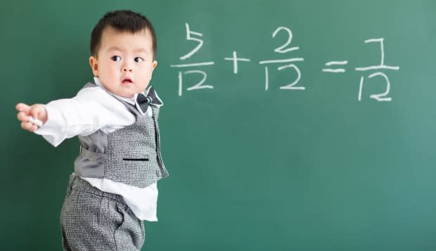Cute baby doing mathematics on blackboard