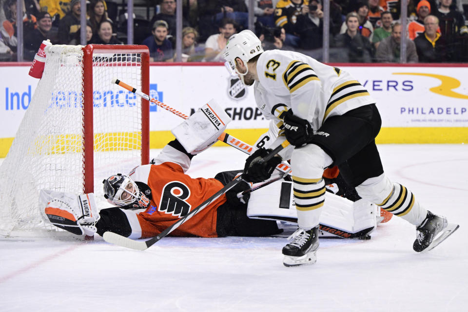 Boston Bruins' Charlie Coyle (13) scores a goal past the reach of Philadelphia Flyers goaltender Cal Petersen, bottom, during the third period of an NHL hockey game, Saturday, Jan. 27, 2024, in Philadelphia. (AP Photo/Derik Hamilton)