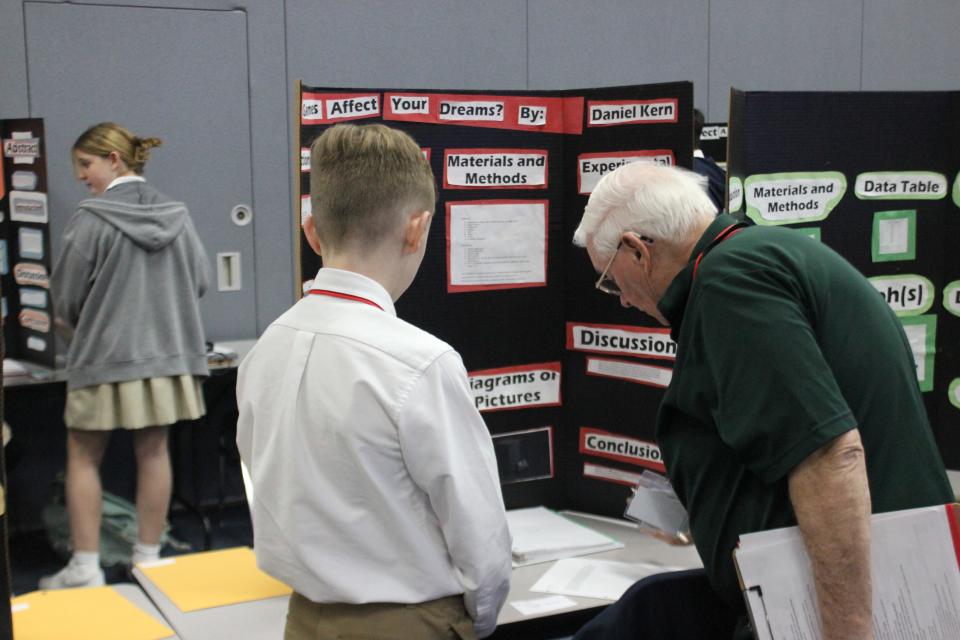 Judge Carl Brown reviews a student's project at the regional science fair Feb. 17.