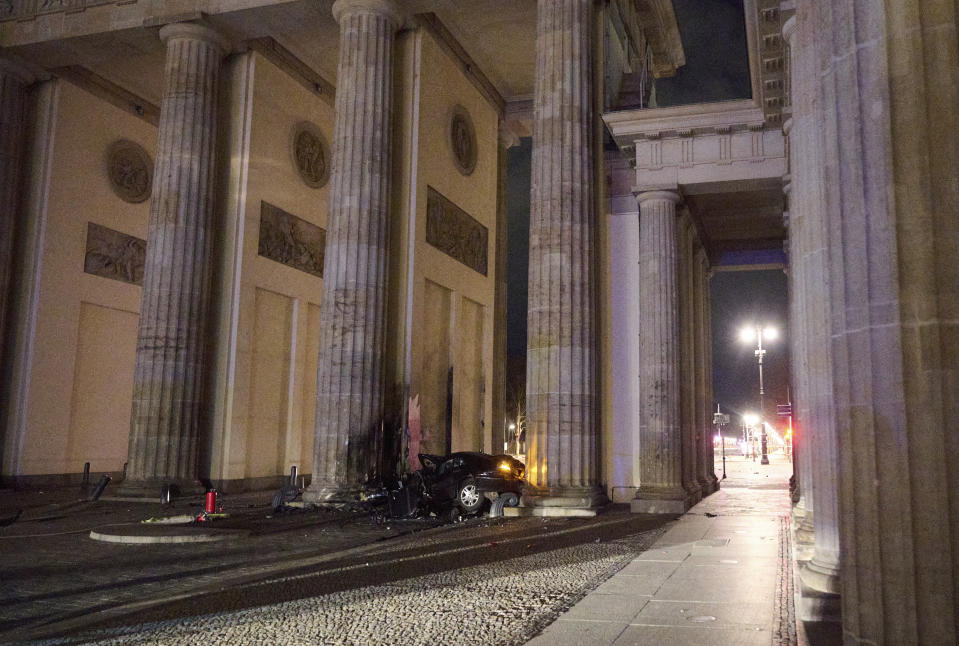 A destroyed car lies between two pillars of the Brandenburg Gate landmark in Berlin, Germany, Monday, Jan. 16, 2023. The car crashed into a pillar of the famous Brandenburg Gate in Berlin. In the car, firefighters found a dead man, said a police spokesman early Monday morning. (Annette Riedl/dpa via AP)