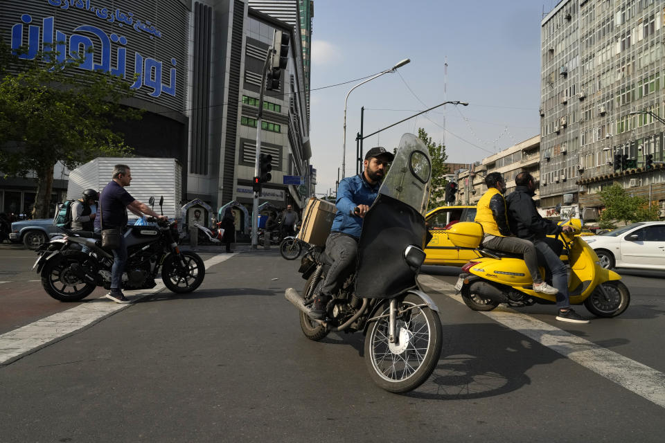 Motorbikes cross an intersection in downtown Tehran, Iran, Sunday, April 14, 2024. Israel on Sunday hailed its air defenses in the face of an unprecedented attack by Iran, saying the systems thwarted 99% of the more than 300 drones and missiles launched toward its territory. (AP Photo/Vahid Salemi)