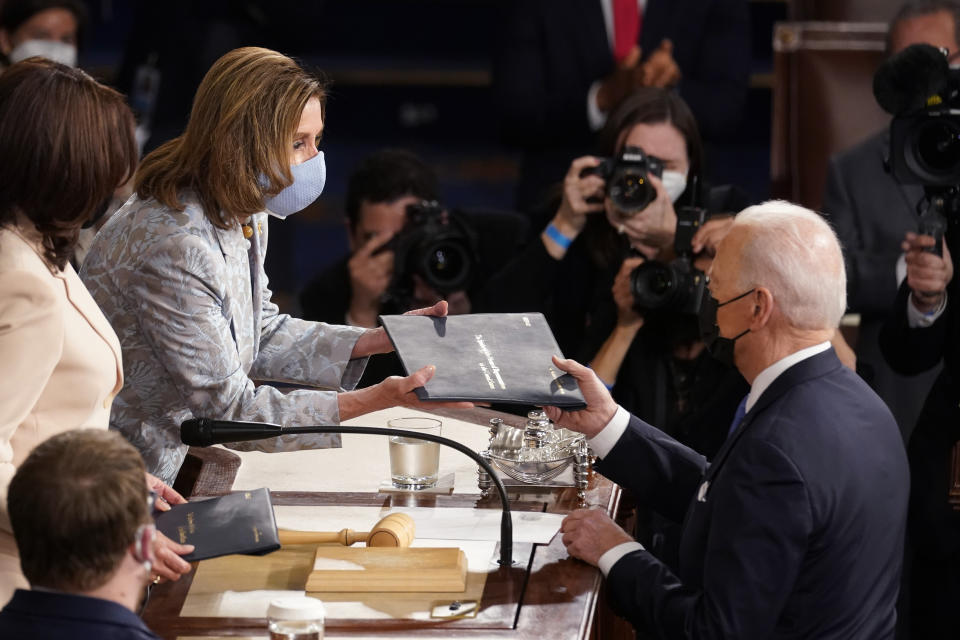 President Joe Biden hands a copy of his speech to House Speaker Nancy Pelosi of Calif., as Vice President Kamala Harris, left, watches as Biden speaks to a joint session of Congress Wednesday, April 28, 2021, in the House Chamber at the U.S. Capitol in Washington. (AP Photo/Andrew Harnik, Pool)