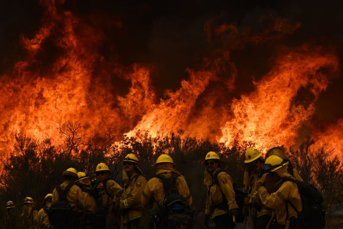 Firefighters turn away to watch for any stray embers during a firing operation to build a line to contain the Fairview Fire near Hemet, California, US (AFP/Getty)