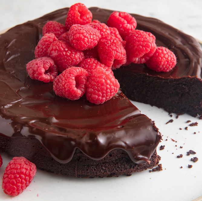 flourless chocolate cake topped with chocolate ganache and raspberries