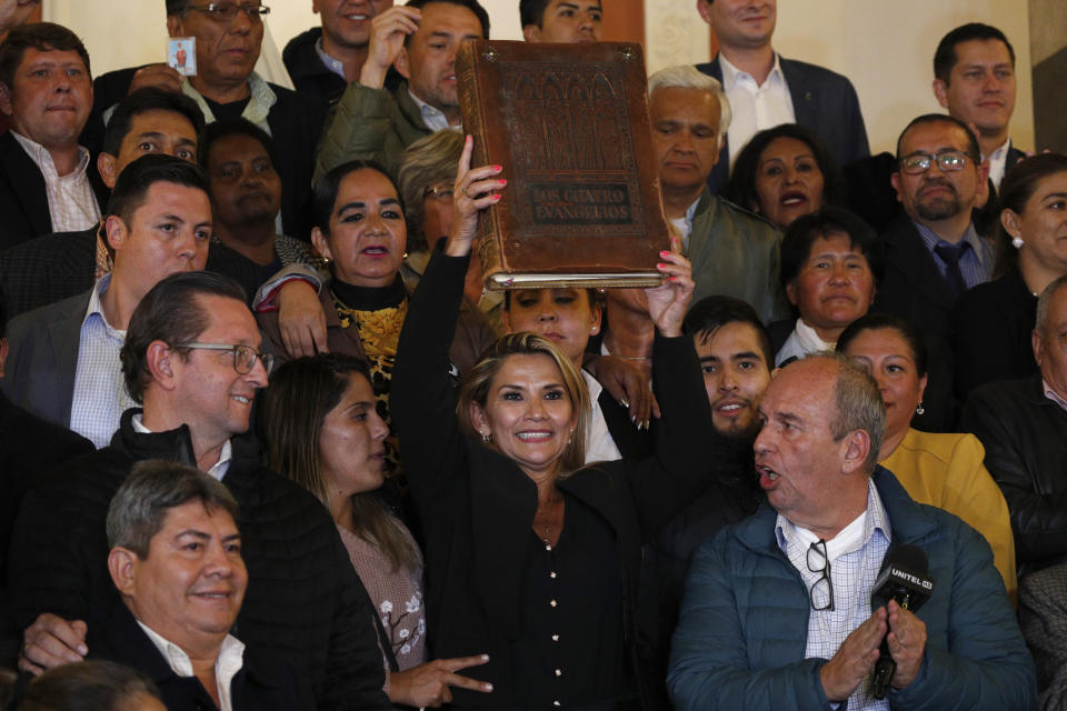 Surrounded by fellow lawmakers, the Senate's second vice president and opposition politician Jeanine Anez, center, holds a Bible after she declared herself the country's interim president during a session at Congress, in La Paz, Bolivia, Tuesday, Nov. 12, 2019. Anez took the step after protests and pressure from the army made former President Evo Morales quit his office. (AP Photo/Juan Karita)