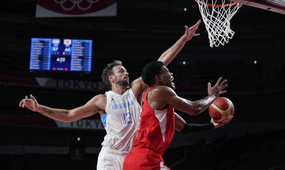 Japan's Rui Hachimura (8), right, drives to the basket over Argentina's Marcos Delia (12) during men's basketball preliminary round game at the 2020 Summer Olympics, Sunday, Aug. 1, 2021, in Saitama, Japan. (AP Photo/Charlie Neibergall)