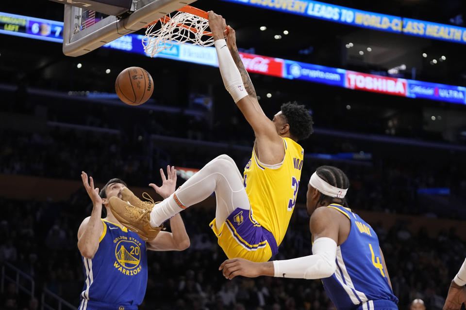 Los Angeles Lakers forward Christian Wood, center, dunks as Golden State Warriors forward Dario Saric, left, and guard Moses Moody defend during the first half of an NBA preseason basketball game Friday, Oct. 13, 2023, in Los Angeles. (AP Photo/Mark J. Terrill)