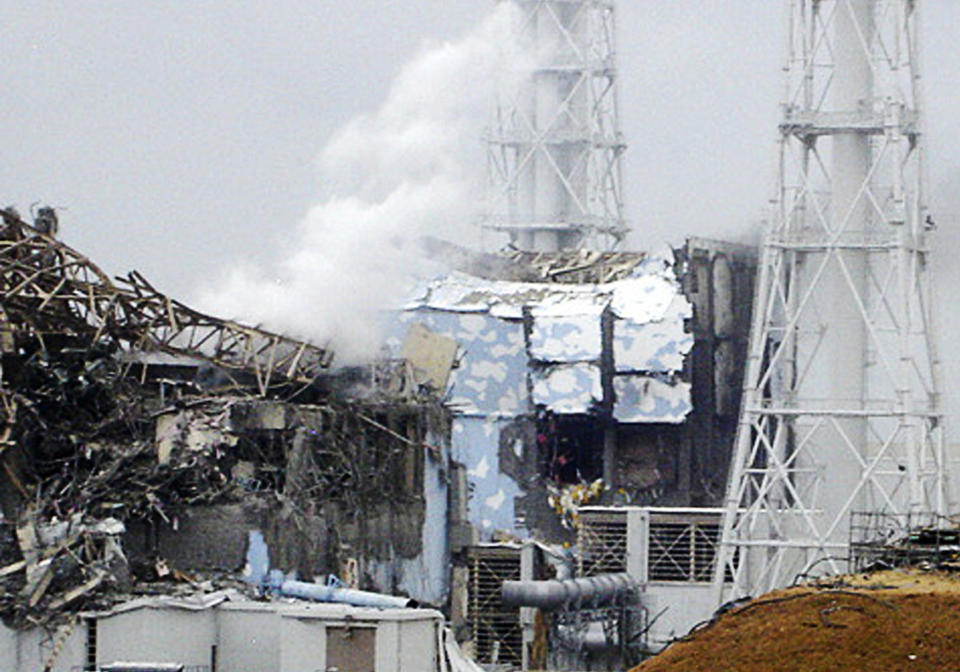 FILE - This file image made available from Tokyo Electric Power Co. via Kyodo News shows the damaged No. 4 unit of the Fukushima Daiichi nuclear complex in Okuma town, northeastern Japan, on Tuesday, March 15, 2011. White smoke billows from the No. 3 unit. A decade ago, the Fukushima Daiichi nuclear power plant melted down. It looked like a bombed-out factory in a war zone. Emergency workers risked their lives as they battled to keep the crisis in check. Eeriness is no longer there. The feeble-looking plastic hoses mended with tape and the outdoor power switchboard that rats got into, causing blackouts, were replaced with proper equipment. (Tokyo Electric Power Co/Kyodo News via AP, File)