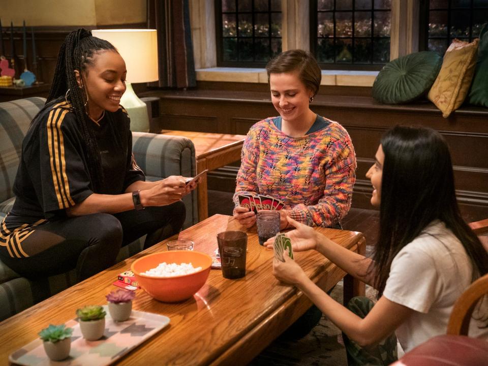 Alyah Chanelle Scott, Pauline Chalamet, Amrit Kaur playing Uno at a table on "The Sex Lives of College Girls."