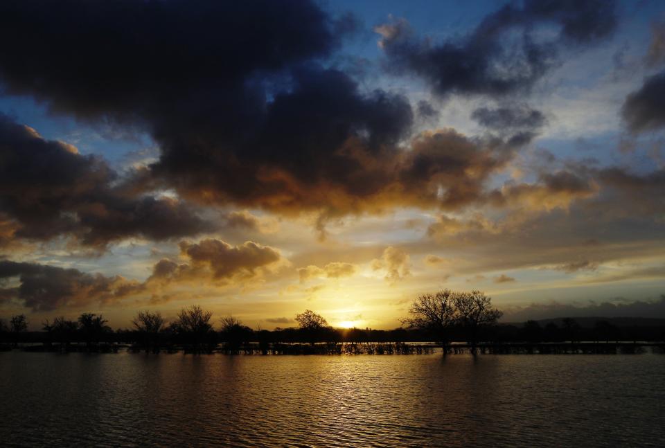 The sun rises over flooded fields at Pulborough in Southern England January 8, 2014. REUTERS/Luke MacGregor (BRITAIN - Tags: ENVIRONMENT SOCIETY)