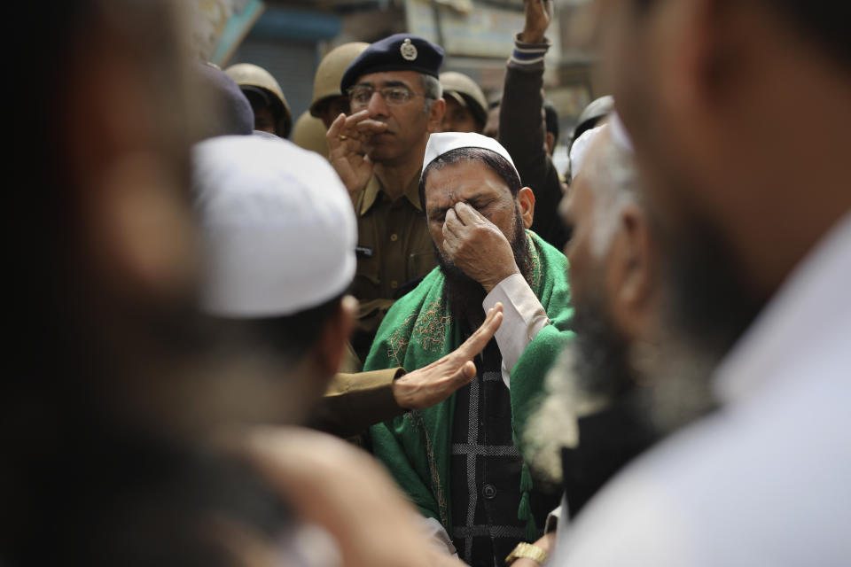 FILE - In this Friday, Feb. 28, 2020, file photo, a man gestures as a senior Delhi police officer speaks to a group of Muslims ahead of Friday prayers near a heavily-policed fire-bombed mosque in New Delhi, India. Many of the Muslim victims of last year's bloody violence say they have run repeatedly into a refusal by police to investigate complaints against Hindu rioters. Some hope the courts will still come to their help. But others now believe the justice system under Prime Minister Narendra Modi's Hindu-nationalist government has become stacked against them. (AP Photo/Altaf Qadri, File)