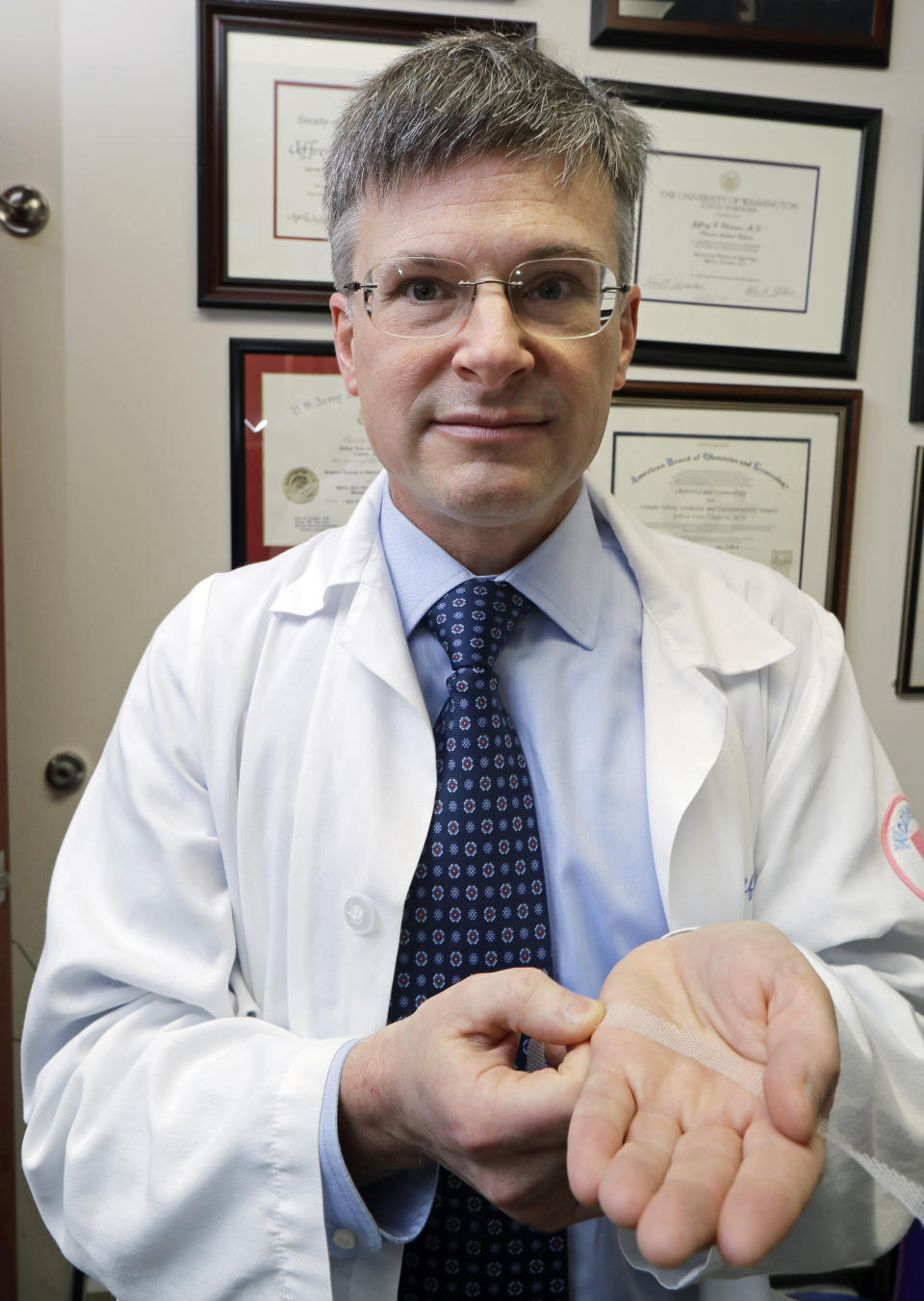 In this Dec. 20, 2018, photo, Dr. Jeffrey Clemons, a pelvic reconstructive surgeon, holds a sample of transvaginal mesh used to treat pelvic floor disorders and incontinence in women as he poses for a photo in Tacoma, Wash. Clemons helped draft a letter to state Attorney General Bob Ferguson that was signed by more than 60 Washington state surgeons, arguing that Ferguson's consumer-protection lawsuit against Johnson & Johnson and its Ethicon Inc. subsidiary over the mesh products might scare patients away from the best treatment options. (AP Photo/Ted S. Warren)