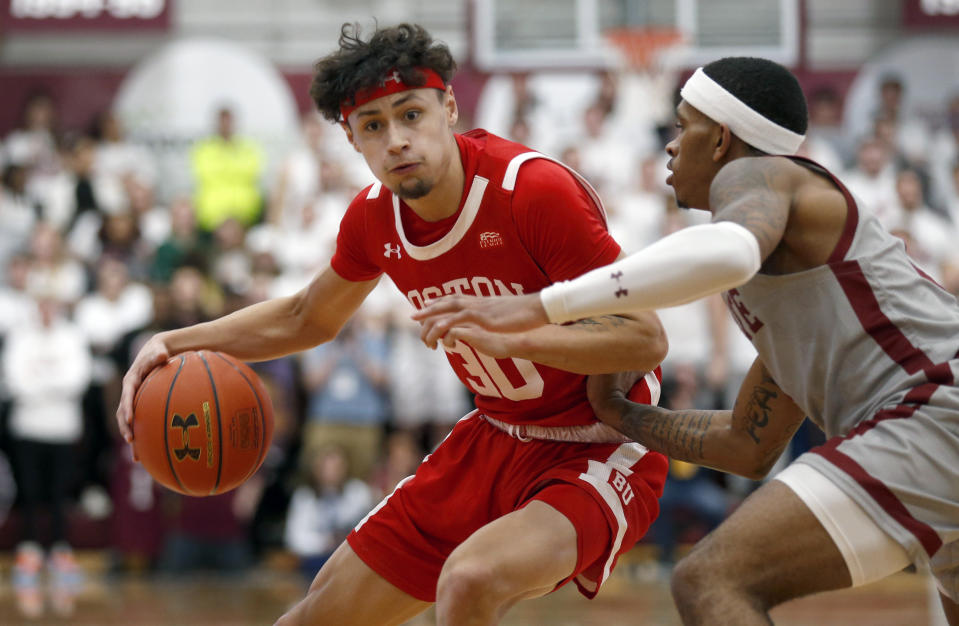 Boston University's Javante McCoy, left, drives past Colgate's Nelly Cummings, right, in the first half of the NCAA Patriot League Conference basketball championship at Cotterell Court, Wednesday, March 11, 2020, in Hamilton, N.Y. (AP Photo/John Munson)