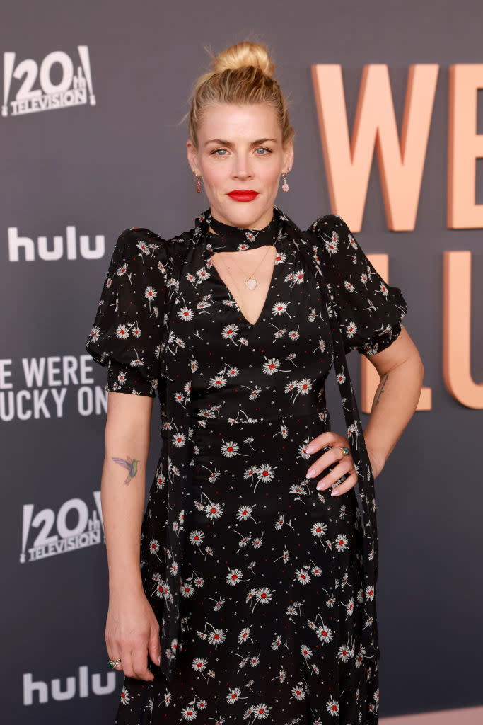 Busy in a floral patterned dress posing on event backdrop