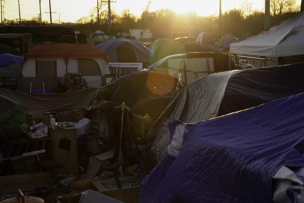 The sun sets over the tops of tents at a homeless encampment on state-owned land in Austin on Jan. 18, 2021.