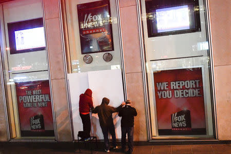 Men place boards over a poster of former cable news host Bill O'Reilly outside of the Fox News offices in Manhattan, New York City, New York, U.S., April 20, 2017. REUTERS/Rashid Umar Abbasi