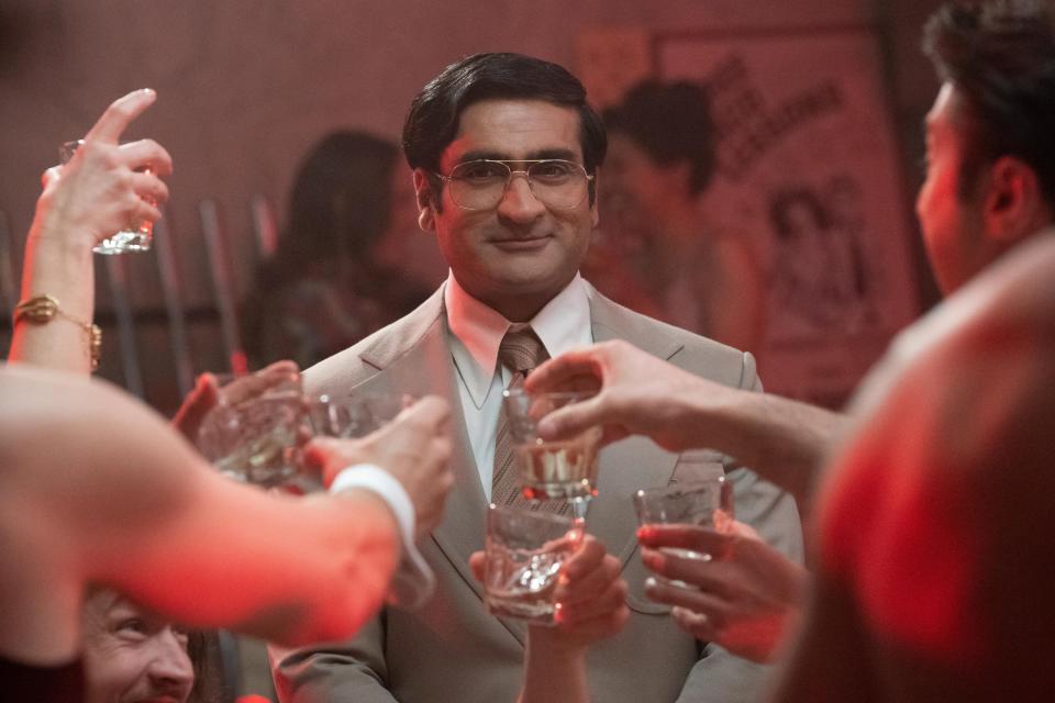 Steve (Kumail Nanjiani) wearing a suit with a group of people toasting to him in a nightclub from the series "Welcome to Chippendales."