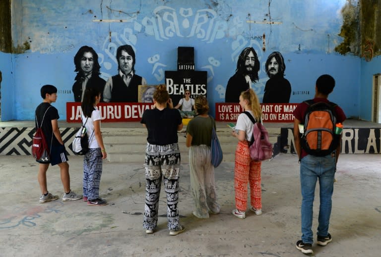 Tourists take pictures of a mural at the now-derelict ashram visited by the Beatles 50 years ago, in Rishikesh in northern India