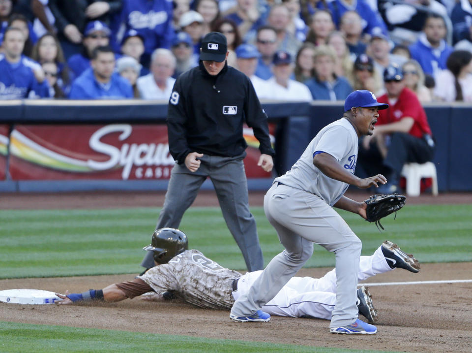 San Diego Padres' Everth Cabrera slides into third safely as Los Angeles Dodgers third baseman Juan Uribe awaits a late throw in the first inning of the opening game of Major League baseball in the United States Sunday, March 30, 2014, in San Diego. (AP Photo/Lenny Ignelzi)