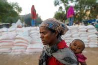 Woman carries an infant as she queues in line for food, at the Tsehaye primary school, in Shire