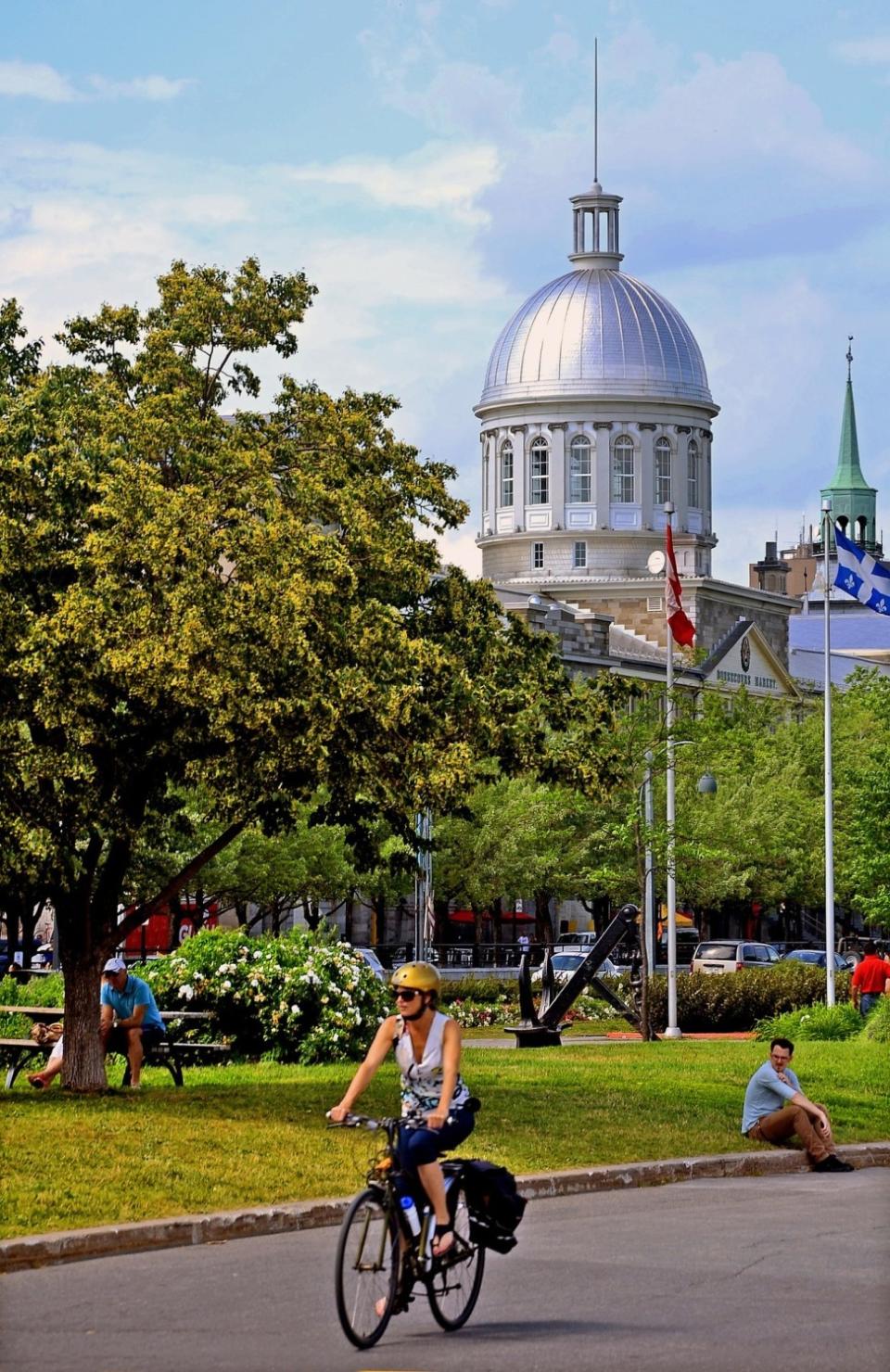 A cyclist rolls through Old Montreal near the dome of the Marché Bonsecours.