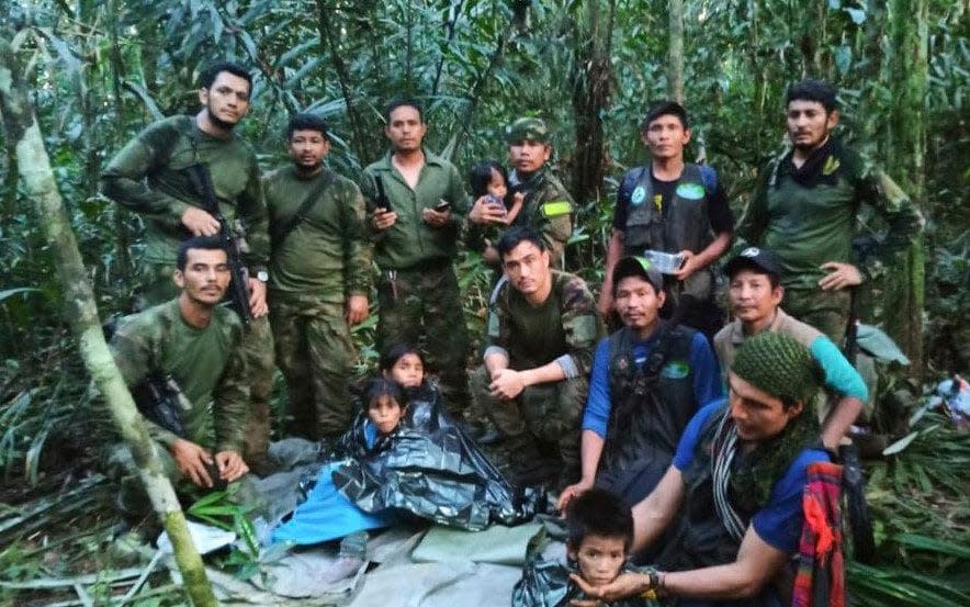 Soldiers and Indigenous men pose for a photo with the four plane crash survivors - Colombia's Armed Force Press Office