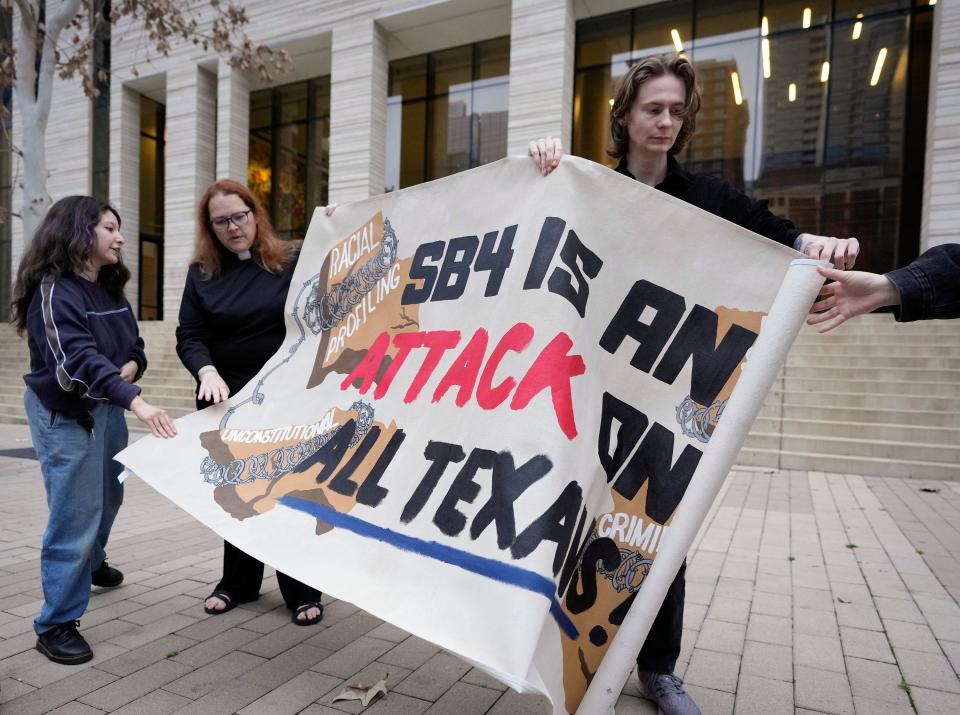 Protesters unveil a banner at a news conference before a February federal court hearing in Austin about the constitutionality of the Senate Bill 4 state immigration law.