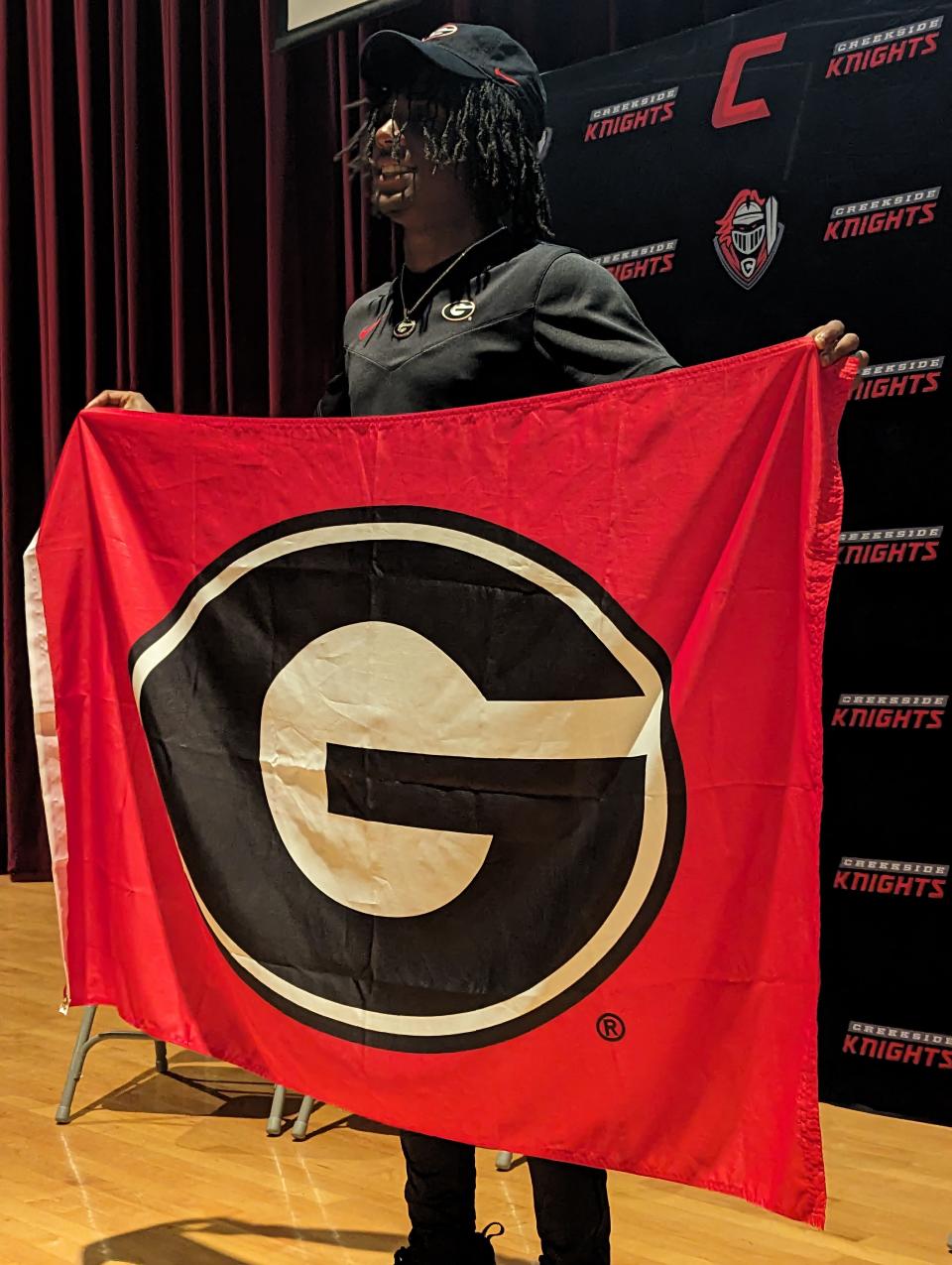 Creekside's Christian Miller holds a University of Georgia flag at his college signing on Wednesday night inside the school auditorium.