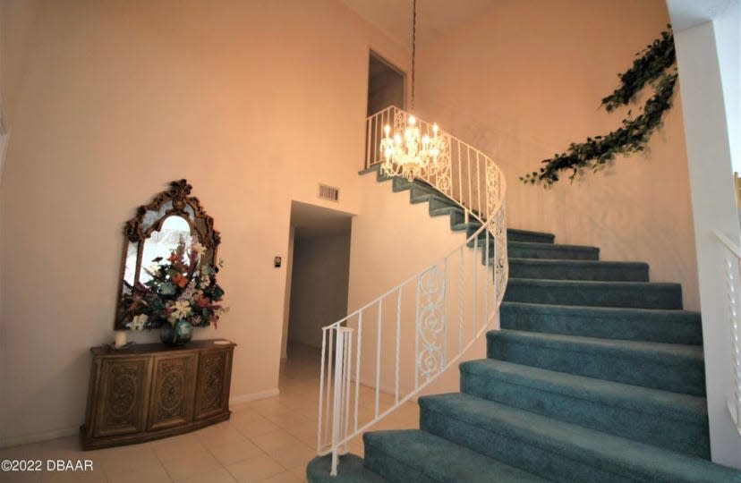 A staircase with elegant wrought-iron railing, leads to the second floor, featuring a balcony that overlooks the lake.