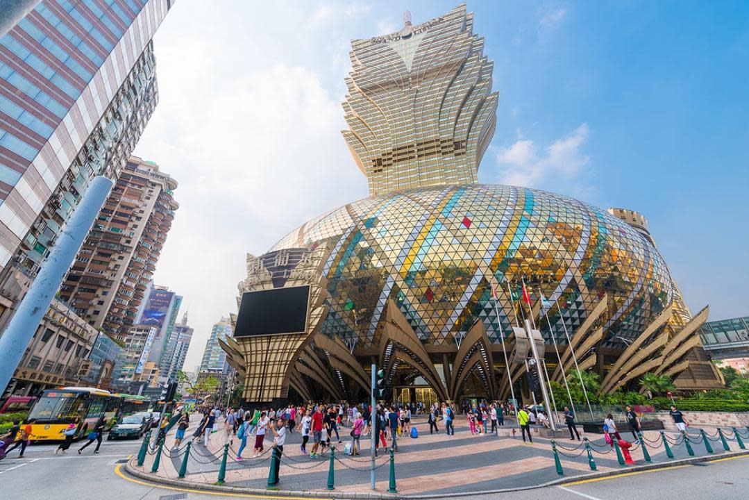 People stroll in front of the Grand Lisboa hotel, the tallest building in Macau.