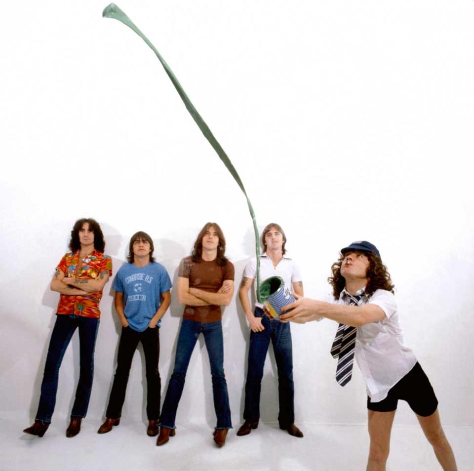 Bon Scott, Malcolm Young, Cliff Williams, Phil Rudd, Angus Young (throwing tin of paint) - posed, studio, group shot