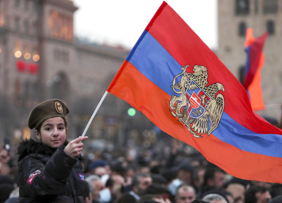 A girl waves an Armenian national flag during a rally of supporters of Armenian Prime Minister Nikol Pashinyan rally in the center of Yerevan, Armenia, Monday, March 1, 2021. Amid escalating political tensions in Armenia, supporters of the country's embattled prime minister and the opposition are staging massive rival rallies in the capital of Yerevan. Prime Minister Nikol Pashinyan has faced opposition demands to resign since he signed a peace deal in November that ended six weeks of intense fighting with Azerbaijan over the Nagorno-Karabakh region. (Hayk Baghdasaryan/PHOTOLURE via AP)