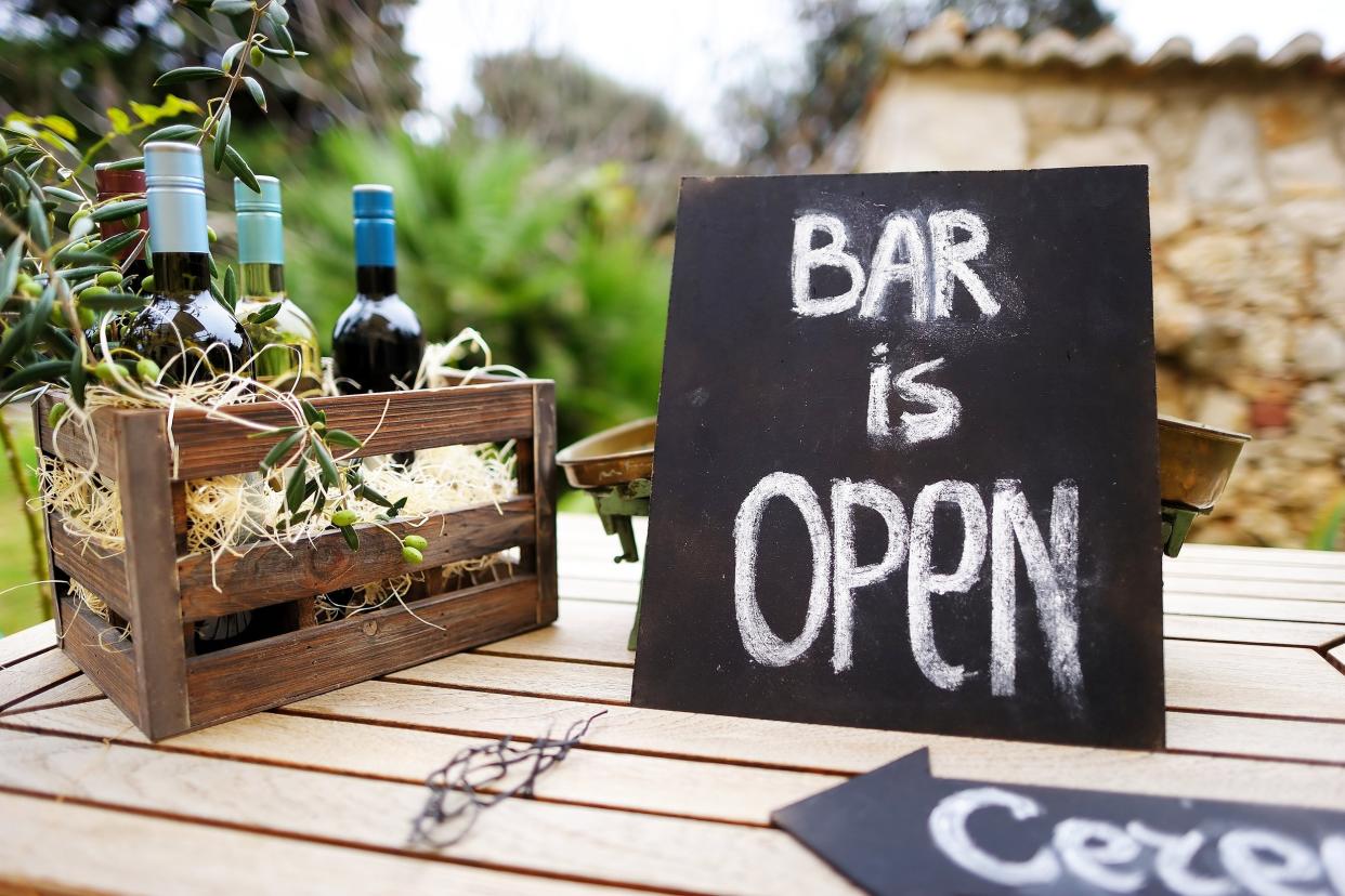 bar is open sign and vintage wooden crate full of wine bottles decorated with olive branches on a table
