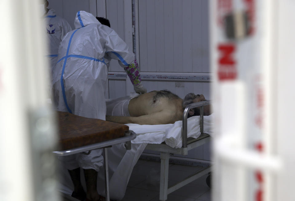 Afghan health workers wrap in a funeral shroud a man who died of COVID-19 at the Afghan-Japan Communicable Disease Hospital in Kabul, Afghanistan, Tuesday June 30, 2020. (AP Photo/Rahmat Gul)