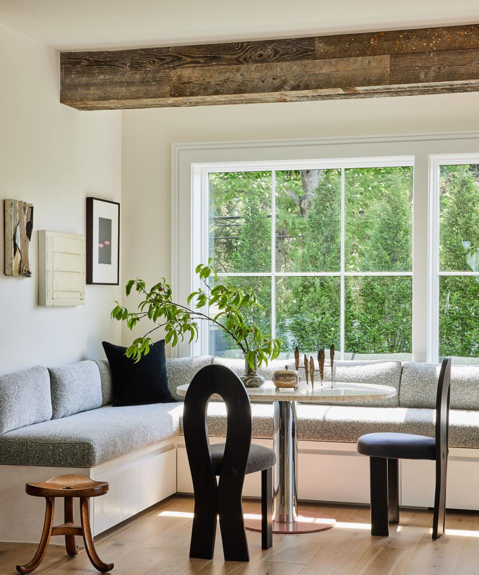 dining nook with white walls and banquette seating black chairs round white table with tubular steel base