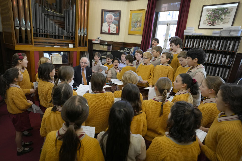 Pupils in the choir gather around the piano to sing with Richard Townend at Hill House School in London, a school where Britain's King Charles III was a pupil, Thursday, April 20, 2023. King Charles III hasn’t even been crowned yet, but his name is already etched on the walls of Hill House School in London. A wooden slab just inside the front door records Nov. 7, 1956, as the day the future king enrolled at Hill House alongside other notable dates in the school’s 72-year history. (AP Photo/Kirsty Wigglesworth)