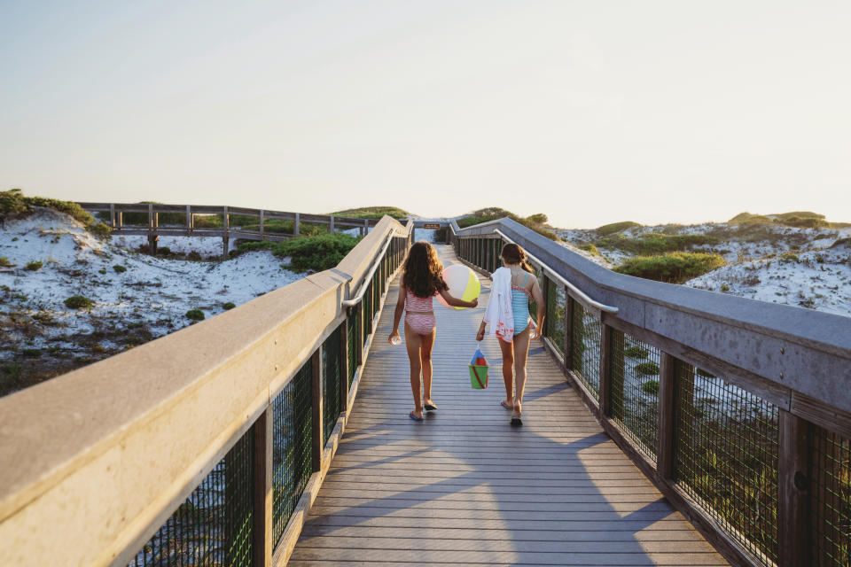 In this June 1, 2019, photo provided by the Florida Department of Environmental Protection, beachgoers walk on a boardwalk at Grayton Beach State Park in Santa Rosa Beach, Fla. The beach earned the first spot of top U.S beaches according to Florida International University professor Stephen Leatherman. The beach was chosen in part because of its sugar-white sand and its clear, emerald-green water. (Courtesy of Florida Department of Environmental Protection via AP)