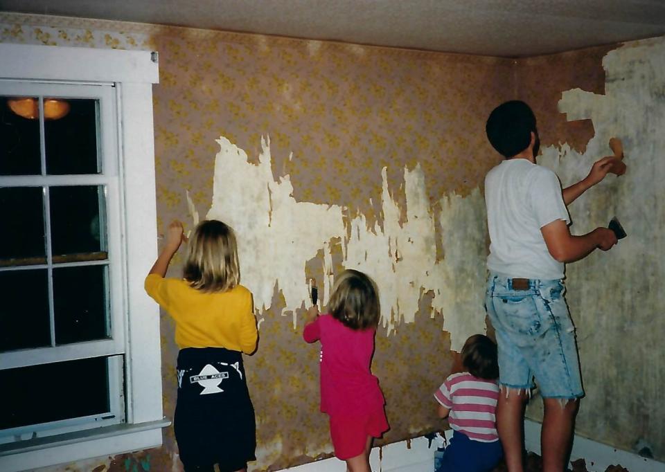 The Miller girls help their dad strip wallpaper from the walls of a bedroom.