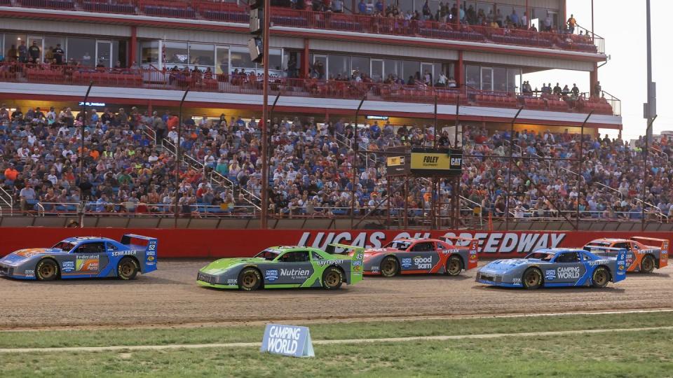 a group of race cars on a track with a crowd watching