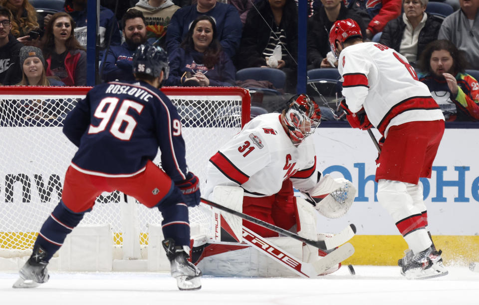 Carolina Hurricanes goalie Frederik Andersen, center, makes a stop between Columbus Blue Jackets forward Jack Roslovic, left, and Hurricanes defenseman Brent Burns during the first period of an NHL hockey game in Columbus, Ohio, Thursday, Jan. 12, 2023. (AP Photo/Paul Vernon)